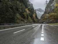a car is driving down an empty highway during the rain and foggy morning, with mountain in the background
