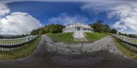 a very big white house on the top of a hill with a driveway near by