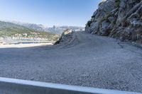 a car drives along a road that is close to a mountain and a large bay