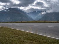 the car is driving down the highway by the mountains on a cloudy day with fog over the peaks