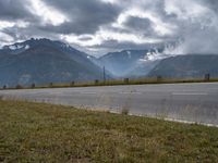 the car is driving down the highway by the mountains on a cloudy day with fog over the peaks