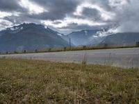 the car is driving down the highway by the mountains on a cloudy day with fog over the peaks