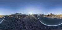 this is a 360 - camera lens of a curved highway near the mountains and in a straight line there is an empty road