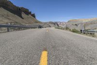 the roadway is lined with smooth gravel road and stone hill terrain with one lane on it