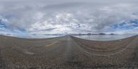 a curved mountain on a partly cloudy day with clouds in the sky as well as the road is empty