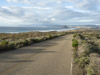 a paved road near the ocean on a partly cloudy day with no traffic to pass