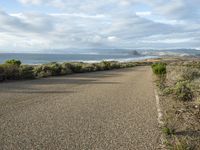 a paved road near the ocean on a partly cloudy day with no traffic to pass