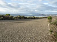 a paved road near the ocean on a partly cloudy day with no traffic to pass