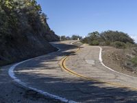 a yellow curve and some rock side next to the highway with a black sign on it