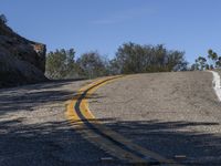 a yellow curve and some rock side next to the highway with a black sign on it