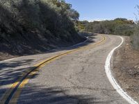 a yellow curve and some rock side next to the highway with a black sign on it