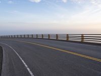 a highway in a scenic area with long railings and the ocean to the far