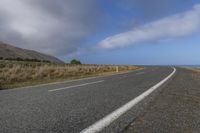 a scenic highway leading to a mountain with a road sign sticking out to the right