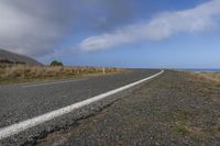 a scenic highway leading to a mountain with a road sign sticking out to the right