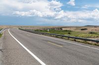 a person riding a horse in the middle of a highway with cloudy skies overhead from the side