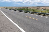 a person riding a horse in the middle of a highway with cloudy skies overhead from the side