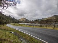 a scenic highway curves next to a small stream of water in a remote mountainous area