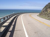 a scenic highway with multiple curves by the water and sky during sunny summer day in california