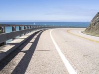 a scenic highway with multiple curves by the water and sky during sunny summer day in california