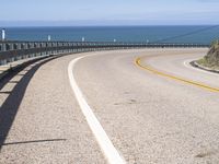 a scenic highway with multiple curves by the water and sky during sunny summer day in california