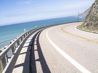 a scenic highway with multiple curves by the water and sky during sunny summer day in california