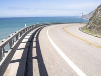 a scenic highway with multiple curves by the water and sky during sunny summer day in california