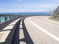 a scenic highway with multiple curves by the water and sky during sunny summer day in california