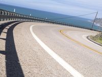 a scenic highway with multiple curves by the water and sky during sunny summer day in california