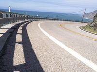 a scenic highway with multiple curves by the water and sky during sunny summer day in california