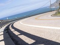 a scenic highway with multiple curves by the water and sky during sunny summer day in california