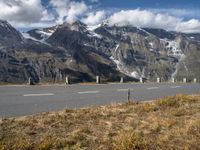 a highway stretches through the middle of a mountainous valley, with some snowy mountains in the distance