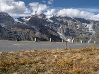 a highway stretches through the middle of a mountainous valley, with some snowy mountains in the distance