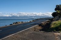 a scenic highway near the water that is very wide by the shoreline and to the mountains