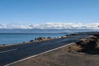 a scenic highway near the water that is very wide by the shoreline and to the mountains