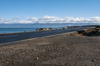 a scenic highway near the water that is very wide by the shoreline and to the mountains