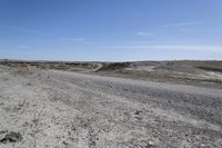 a dirt road is surrounded by some hills and desert like terrain as the vehicle sits on it