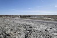 a dirt road is surrounded by some hills and desert like terrain as the vehicle sits on it