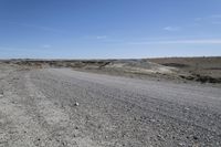 a dirt road is surrounded by some hills and desert like terrain as the vehicle sits on it