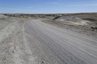 a dirt road is surrounded by some hills and desert like terrain as the vehicle sits on it