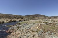 a person with a backpack is walking on a rocky path next to a river in a forested area