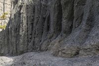 people walking through a rocky canyon below a waterfall, with the mountains to the side