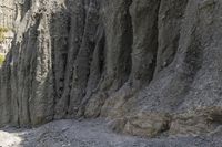 people walking through a rocky canyon below a waterfall, with the mountains to the side