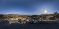 a panorama of a scenic hill top with benches overlooking the mountains and a full moon