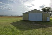 two large grain bins sit in the center of a field, surrounded by silos