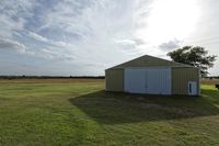 two large grain bins sit in the center of a field, surrounded by silos