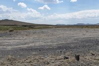 a lone elephant on a dirt land with mountains in the background with no people or animals