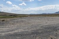 a lone elephant on a dirt land with mountains in the background with no people or animals