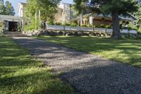 a pathway with rocks that have been placed near a house and trees in the background