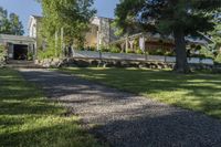 a pathway with rocks that have been placed near a house and trees in the background