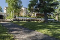 a pathway with rocks that have been placed near a house and trees in the background